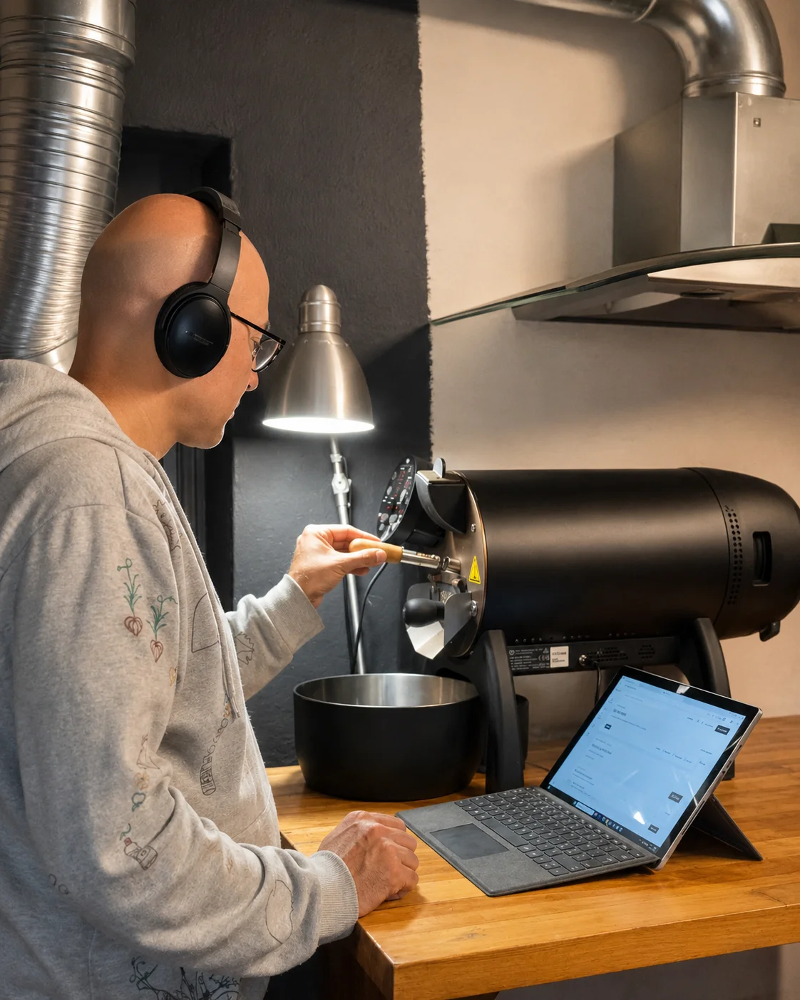 Omid at the roaster at Haimoo Roastery, with the software open on a tablet on the workbench.